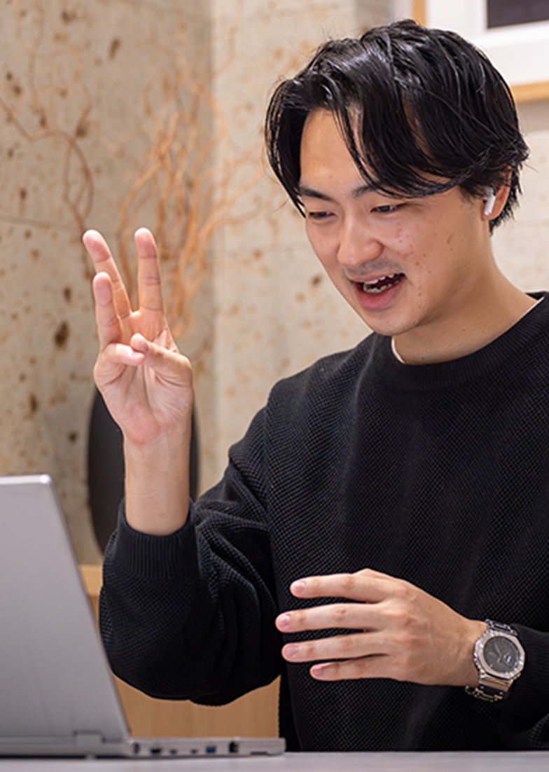 ノートパソコンを前に手振りを交えて何かを伝えている様子