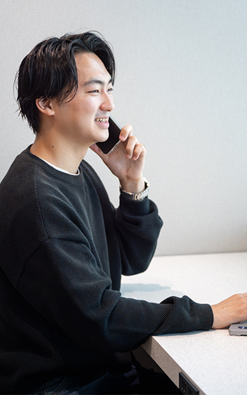 スマートフォンで通話しながらノートPCで作業している様子